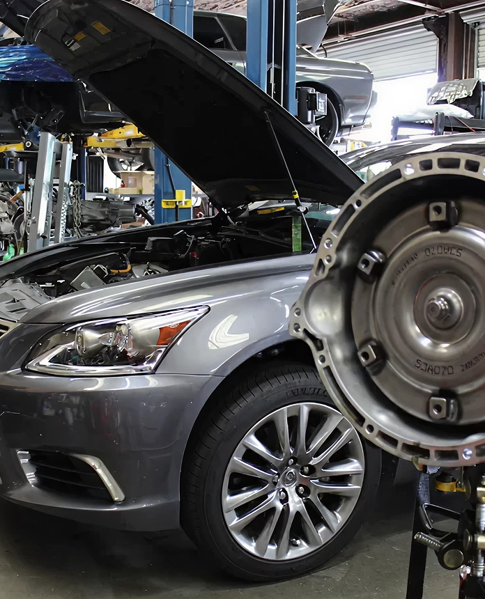 Close-up of a car in an automotive shop with the hood open, showcasing mechanical components and repair tools.