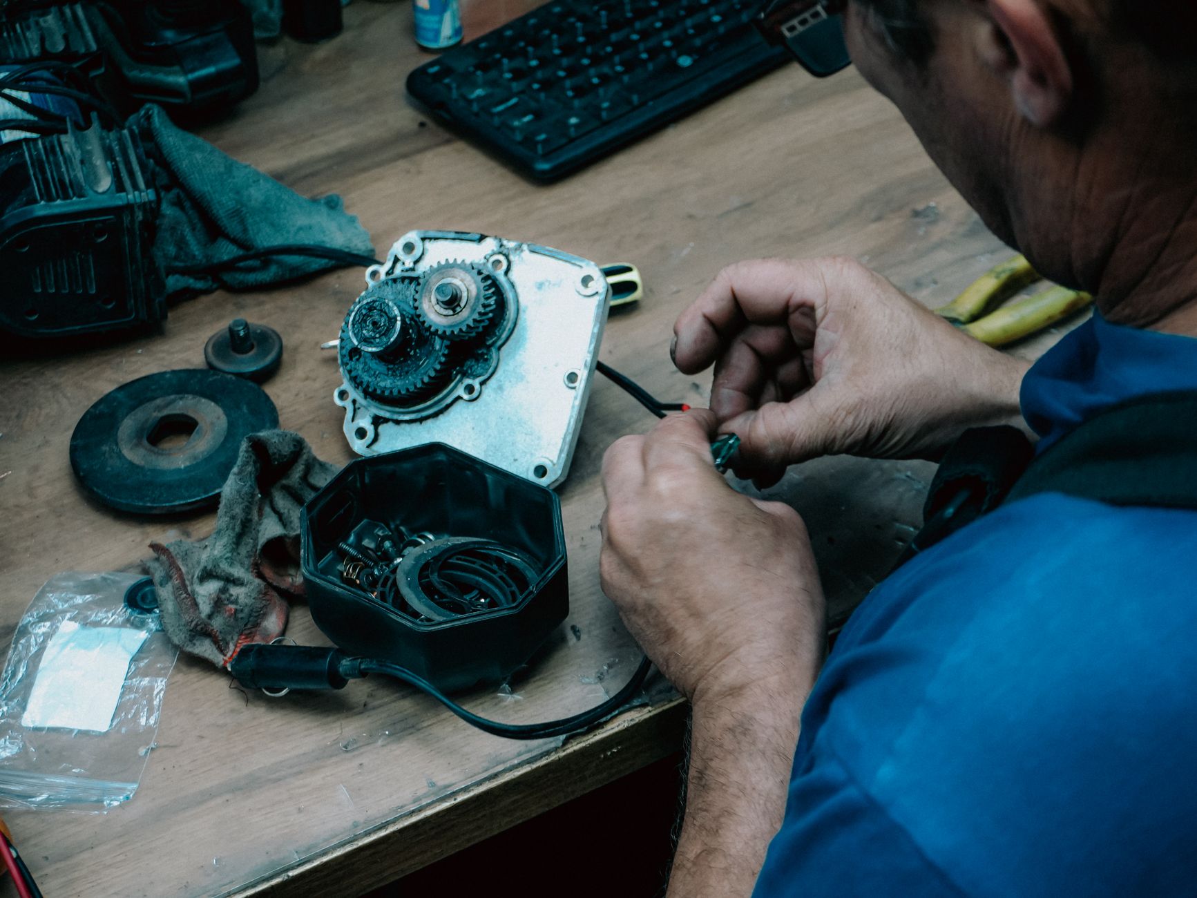 An adult male technician repairing a mechanical gear system on a wooden table indoors. — 3 Secrets of a Effective Preventive
