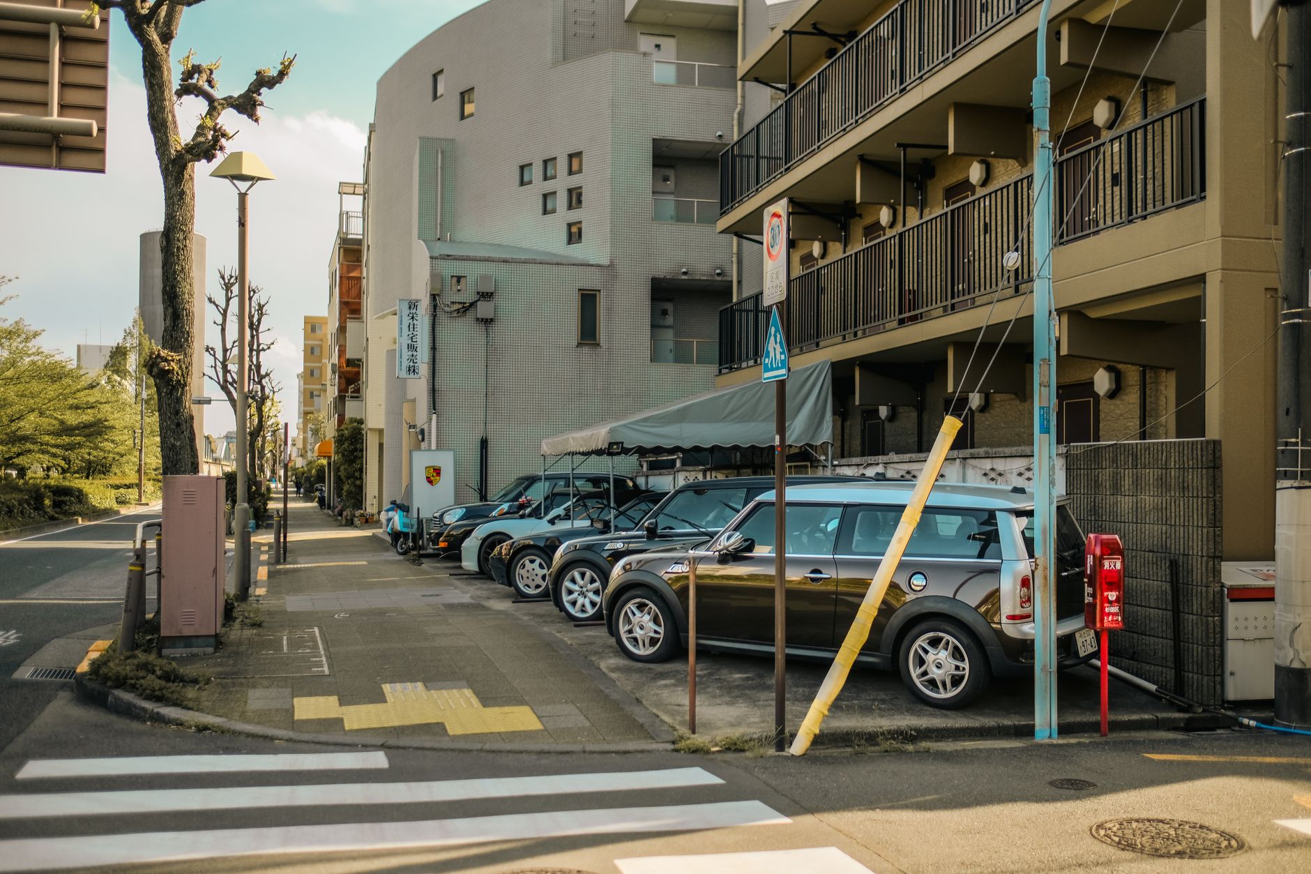 A street view capturing parked cars alongside residential buildings on a sunlit day. — A guide to use the baby monitor for nu