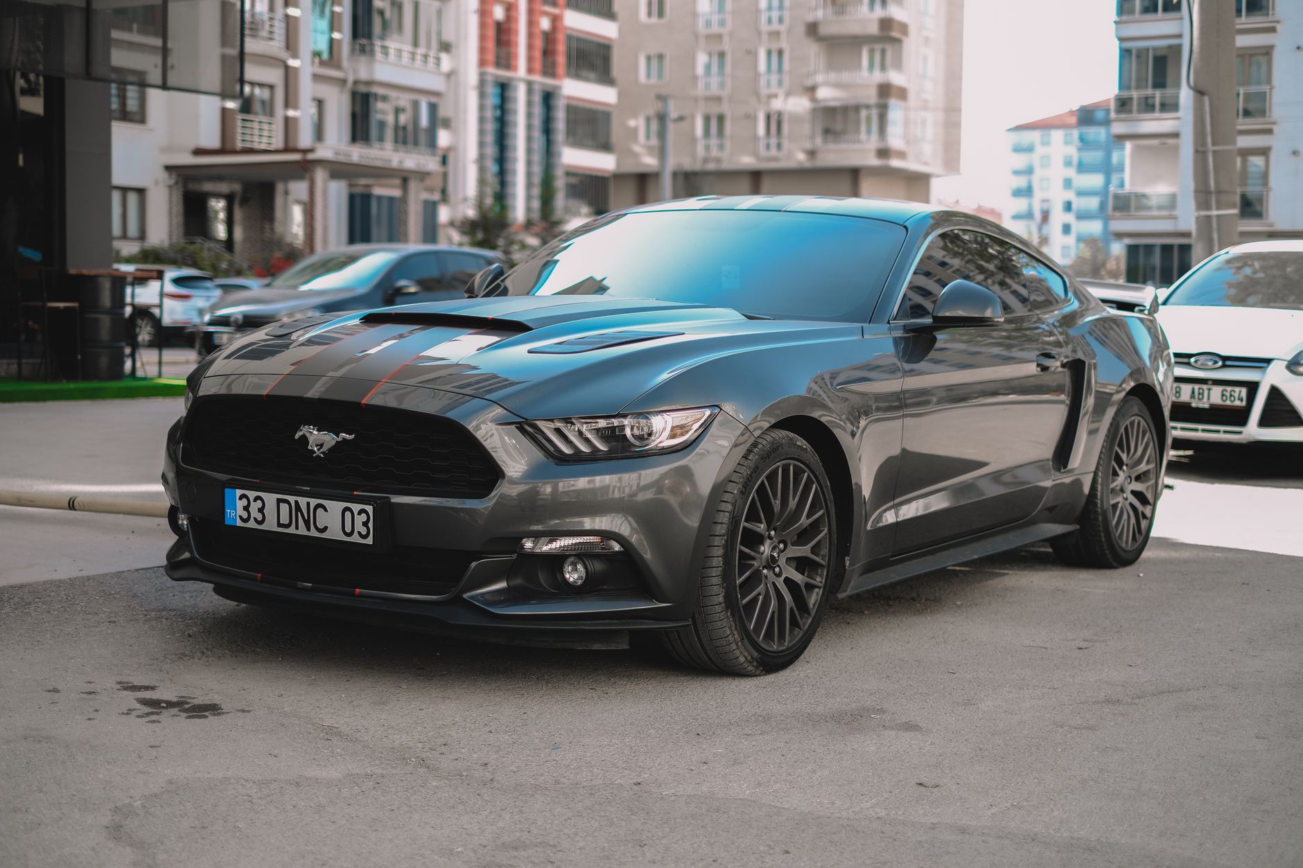 A stylish black Ford Mustang parked on a city street, showcasing its sporty design in a modern urban environment. — Best Junk