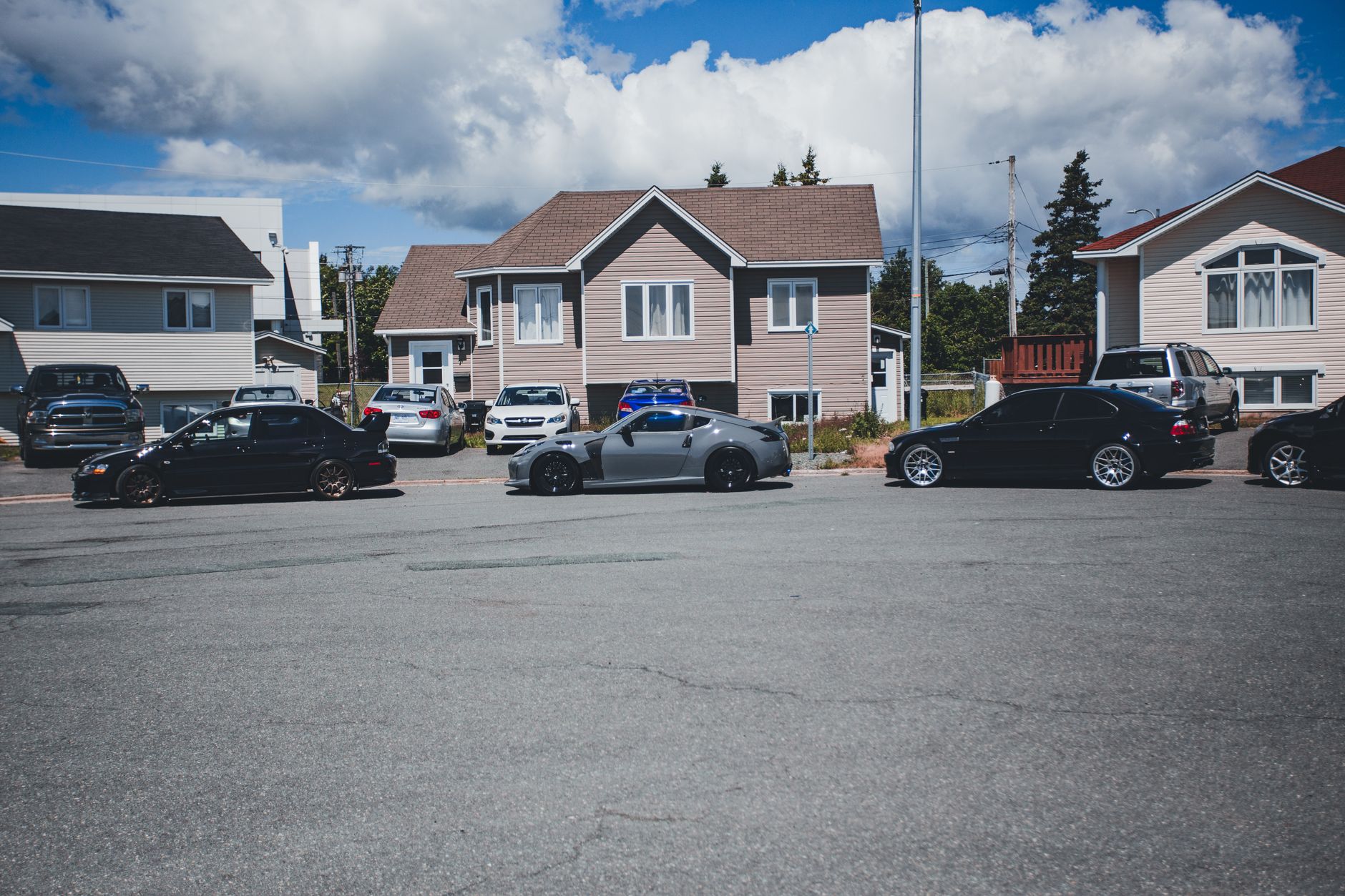 Sunny neighborhood street with modern homes and parked vehicles on a bright day. — Choose the web source wisely while selling