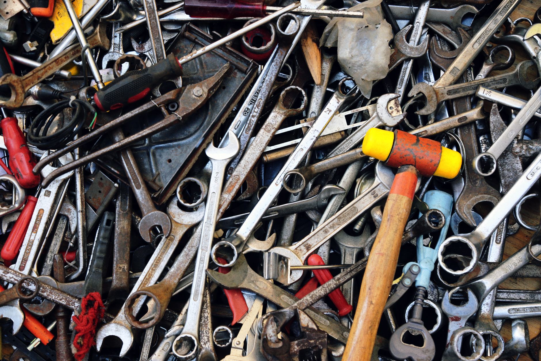 Close-up view of various tools including wrenches and a hammer, providing a cluttered yet organized look. — Customer Support