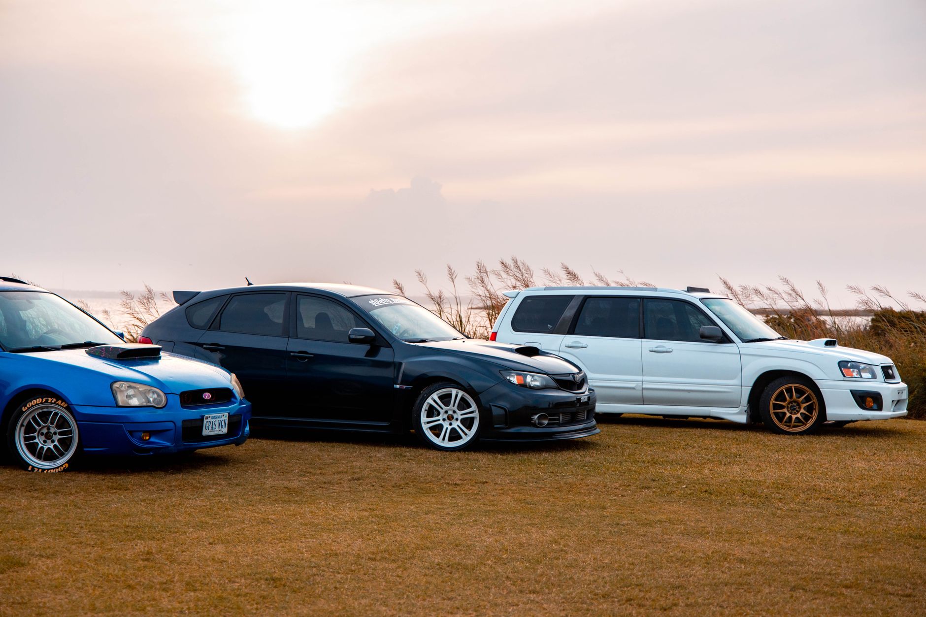 Three Subaru cars parked on a grassy field during sunset, suggesting a relaxing automotive scene. — Everything You Need To Kn