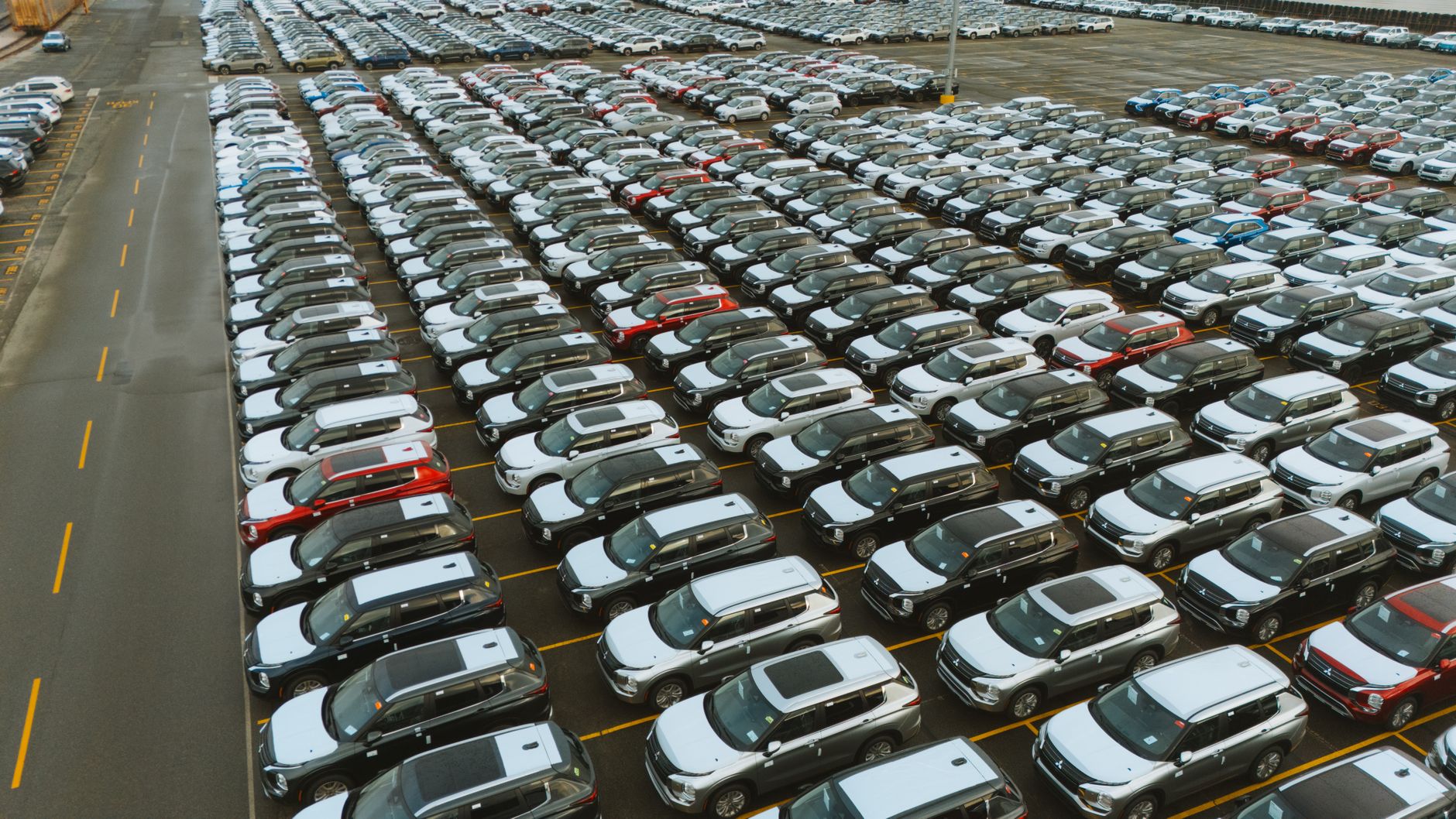 Aerial shot of an extensive car parking lot filled with new vehicles ready for distribution. — How can you explore the best w
