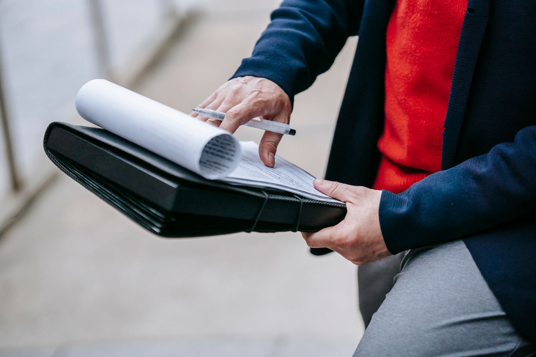 Close-up of a professional person reviewing documents outdoors. Engaged in work with focus on writing materials. — Internatio