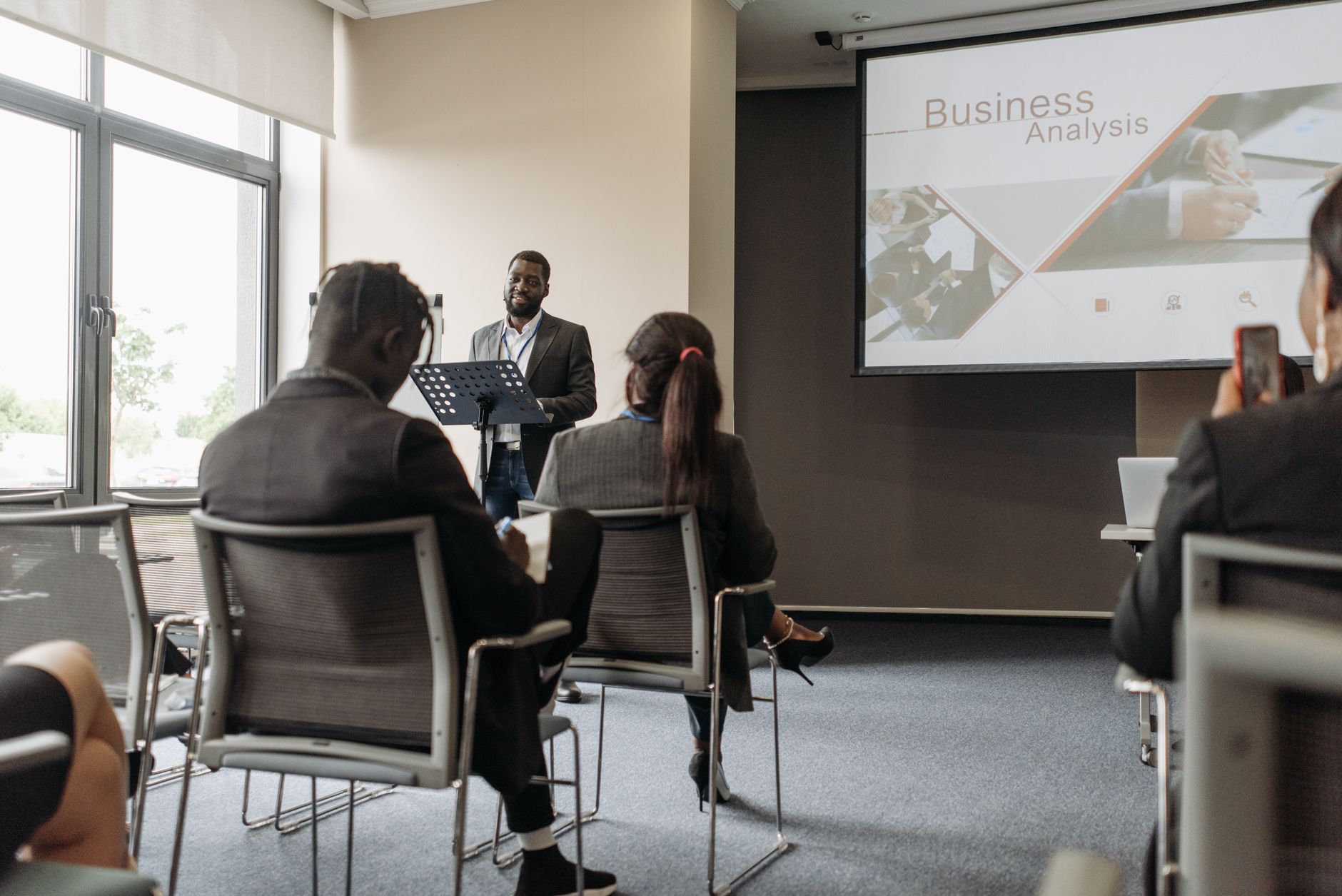 A business professional delivering a presentation in a conference room with diverse attendees. — London Erotic Massage: Unwin