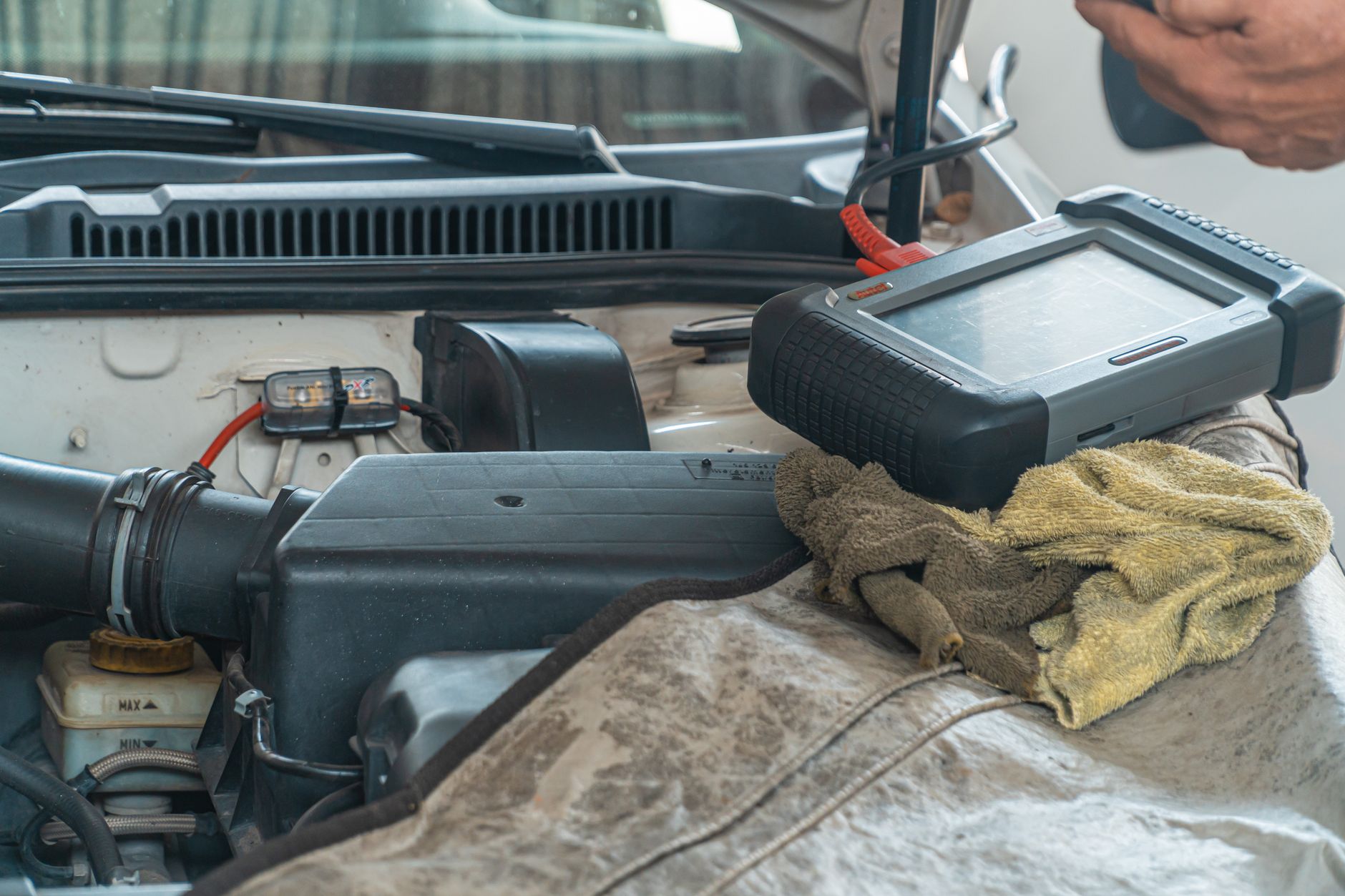 Close-up of a car engine inspection using a diagnostic tool in a garage setting, showcasing automotive maintenance and repair