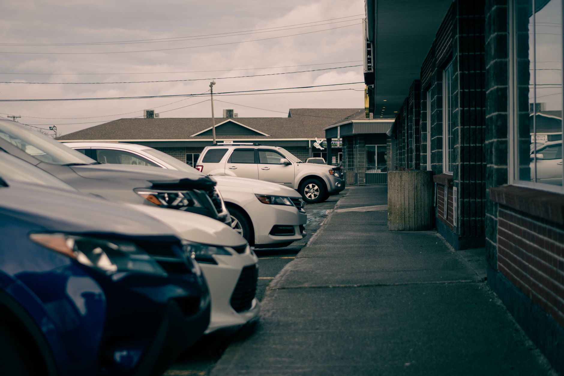 Row of contemporary automobiles parked against walkway and house facades under cloudy sky in town — Polish your car like a Pr