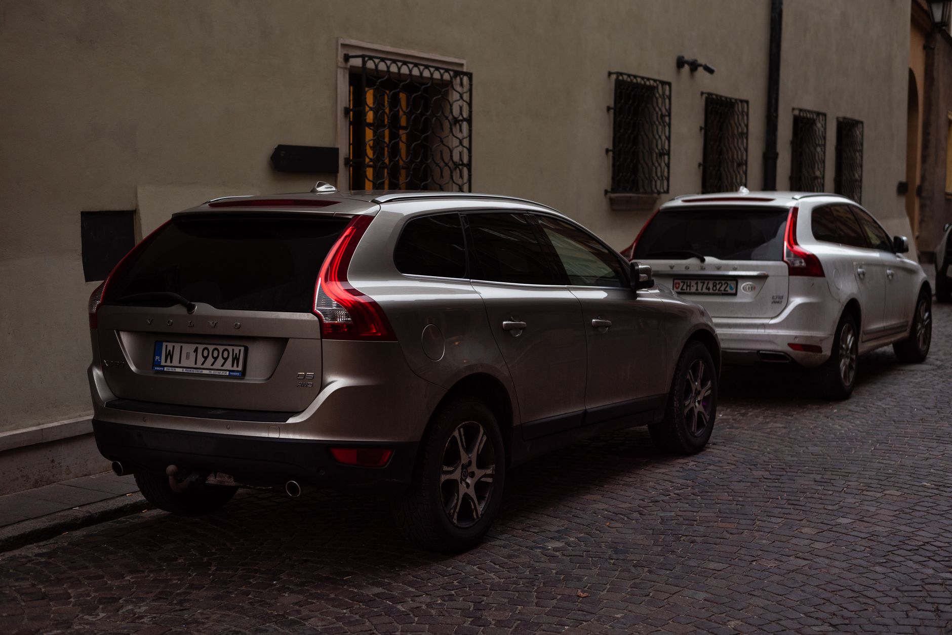 Evening urban scene with two parked SUVs on a cobblestone street. — Renting A Car For Your Trip: Know The Fees At Entirety