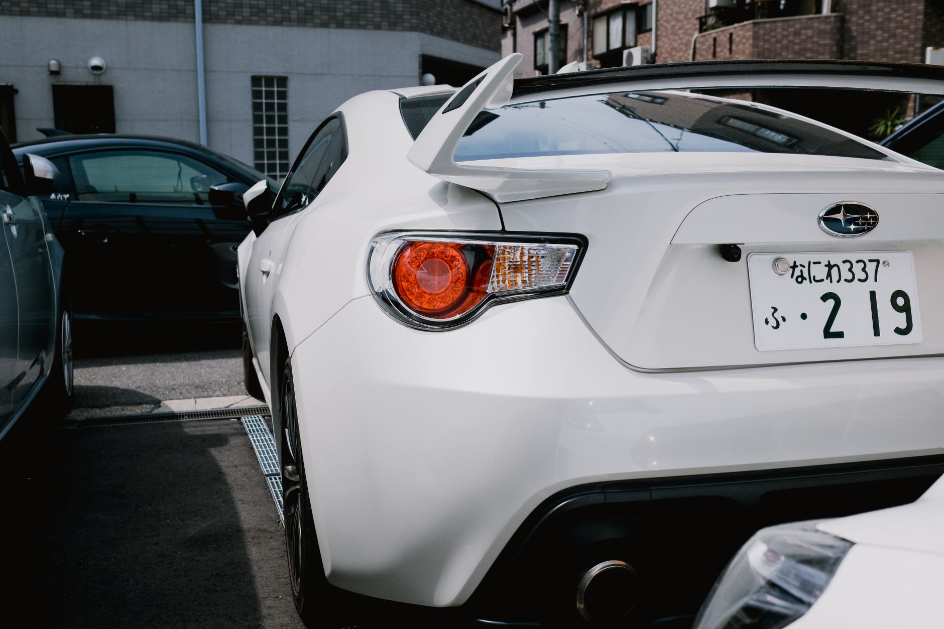 A stylish white Subaru BRZ parked in a city lot, showcasing its sporty rear design. — Selling your vehicle is done by your op