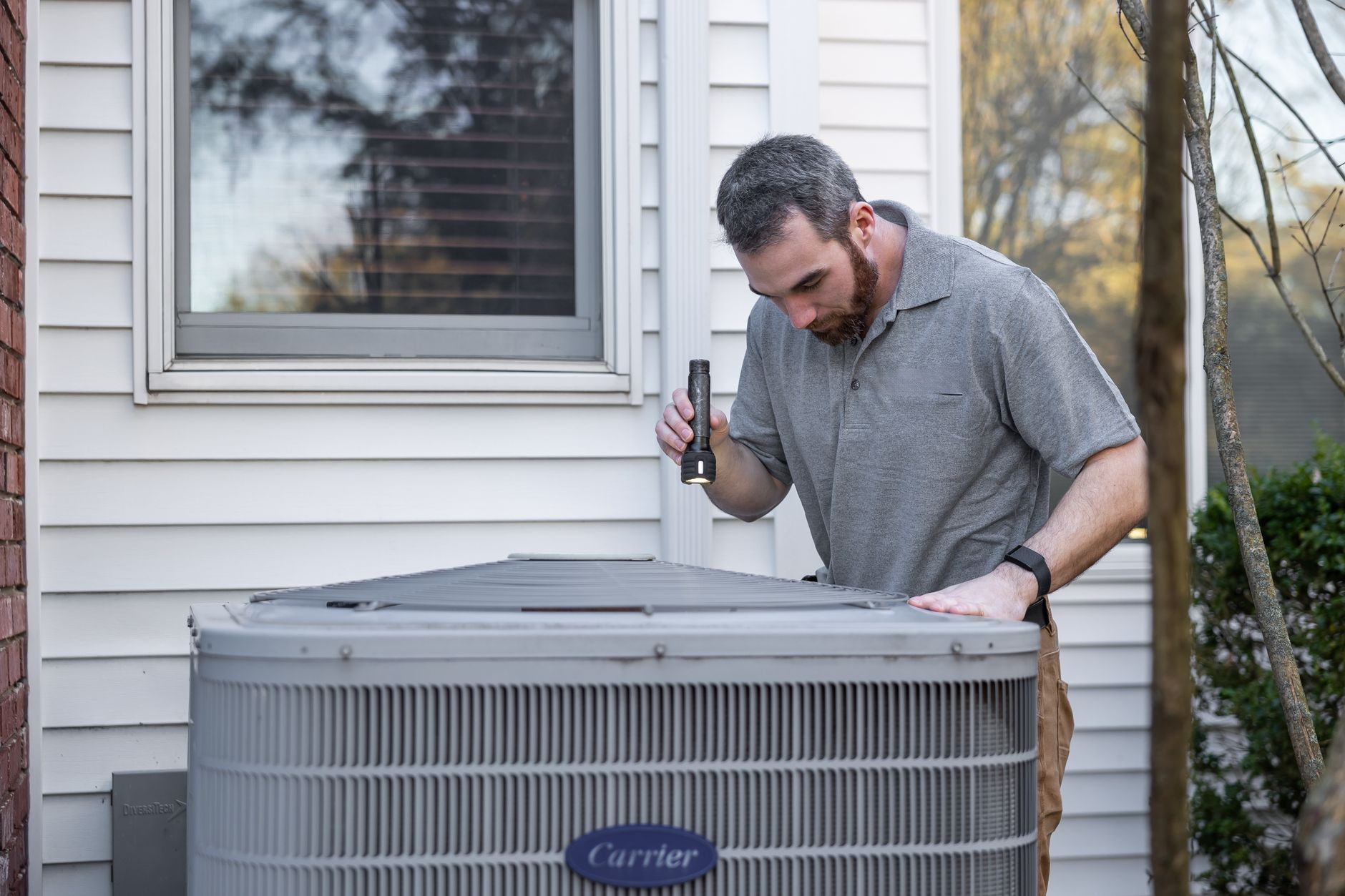 A technician inspects an outdoor HVAC unit for maintenance. — Some equipment used by auto body shop for repairing cars