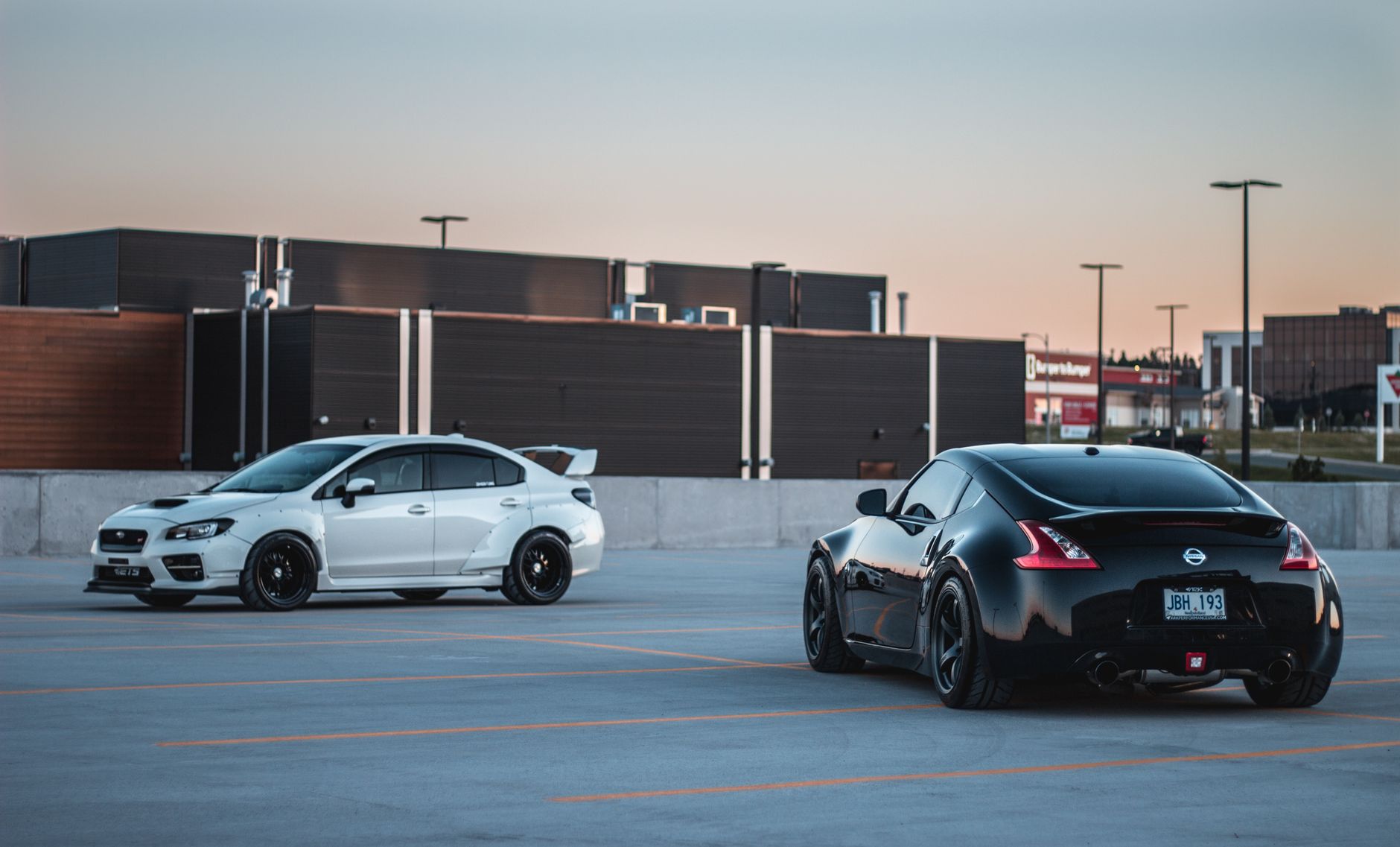 Shiny various contemporary sports cars riding on parking area near modern building against cloudless sundown sky — Test Drive