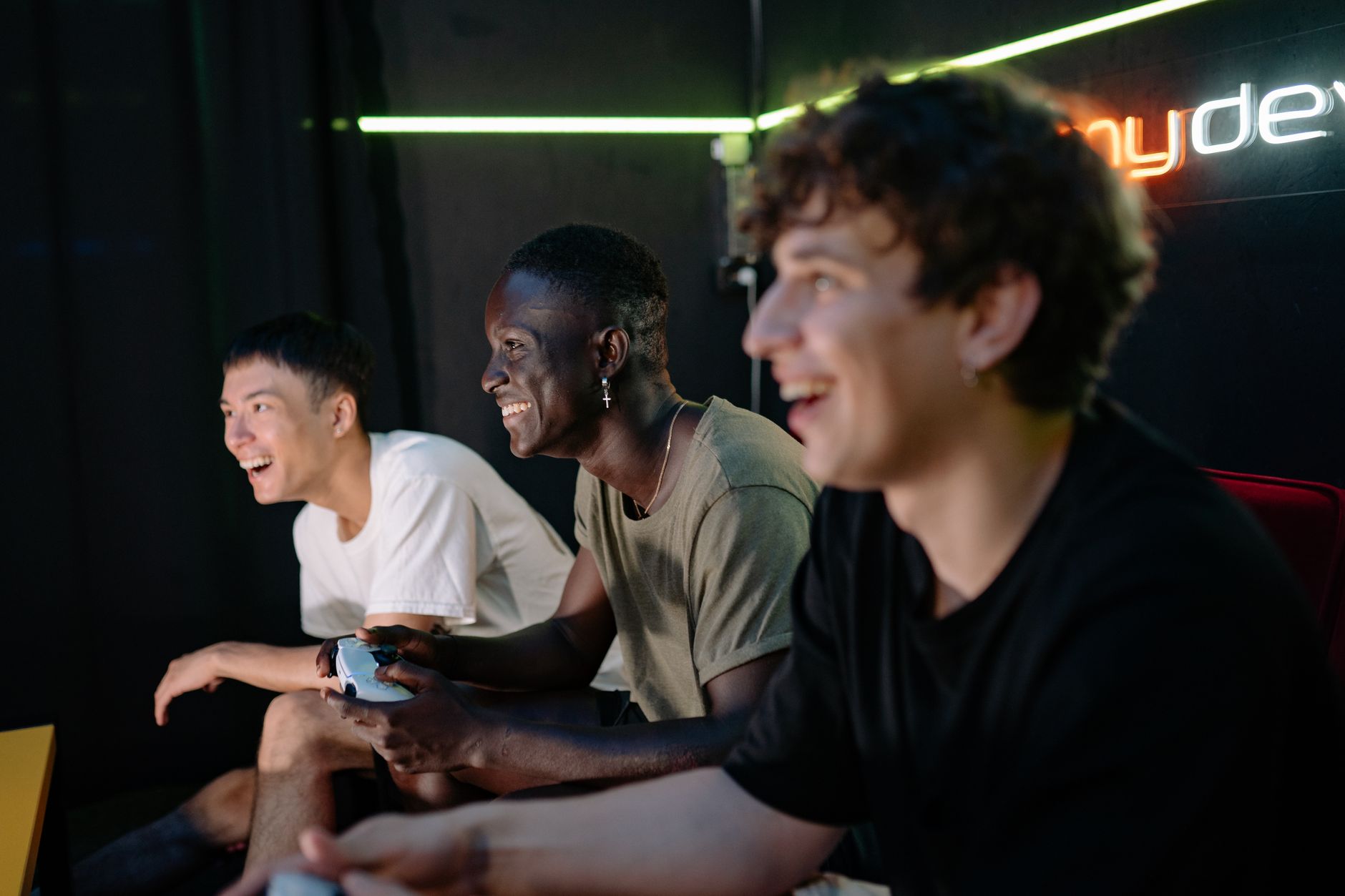Three diverse young men playing video games indoors, showing excitement and enjoyment. — Things to Know About Using Game Hack