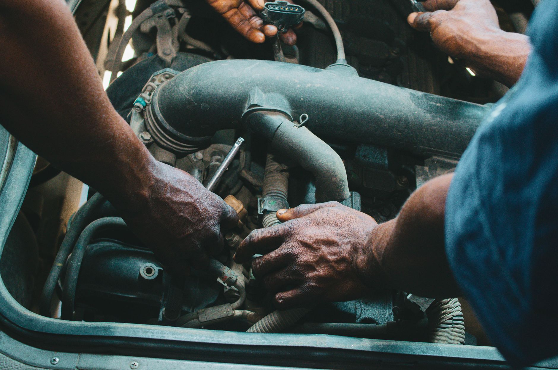 Close-up of mechanics working on a vehicle engine, showing teamwork and precision in car maintenance. — Understand More About