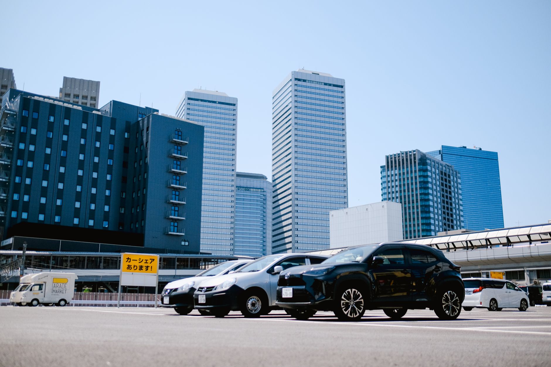 City parking lot with modern buildings and parked cars under a clear sky. — Used Car Loans: a Luxury you can Afford
