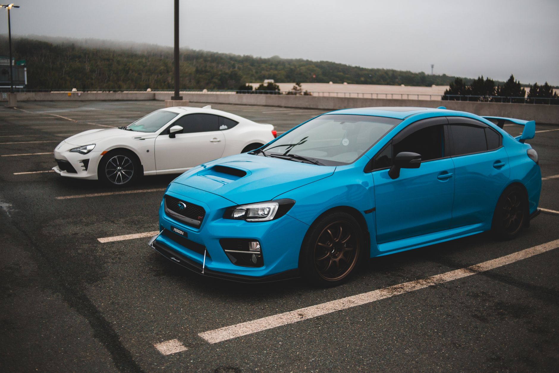 Modern fast clean automobiles parked on concrete surface with stripes on gloomy cloudy day — Used vs Brand New Car: Which Is
